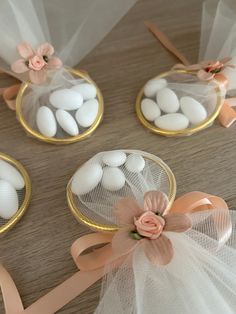 four small baskets filled with white eggs on top of a wooden table next to ribbons