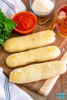 breadsticks on a cutting board with sauce and parsley