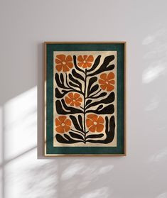 an orange and black flowered design on a white wall with shadow from the window