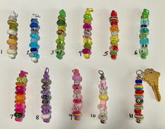 a bunch of different colored beads and keychains on a white surface with numbers in the middle