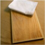 two wooden cutting boards sitting on top of a brown table next to a white napkin