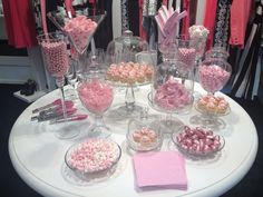 a table topped with lots of pink and white candies on top of glass bowls