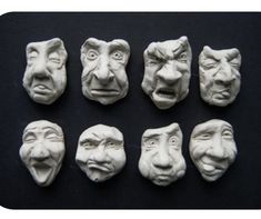 six clay masks with different facial expressions on black background, including one man's face