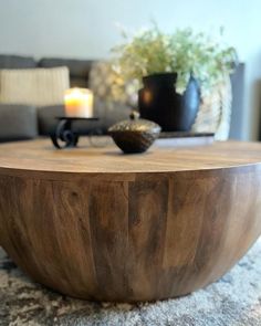 a wooden table sitting on top of a carpeted floor next to a couch and potted plant