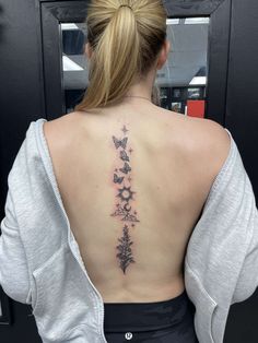 the back of a woman's neck with flowers and butterflies tattooed on her lower back