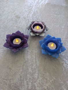 three candles sitting on top of a table next to each other with flowers in the middle