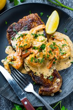 steak in creamy cajun shrimp sauce on a plate with lemon wedges