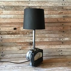 a lamp that is on top of a wooden table next to a wall with wood planks