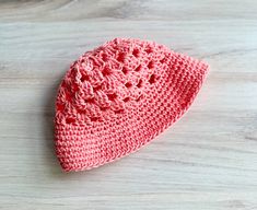 a crocheted pink hat sitting on top of a wooden table