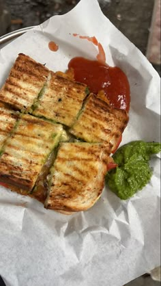 a grilled sandwich with tomato sauce and lettuce sits on a paper wrapper