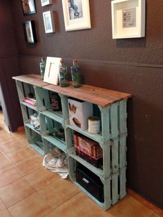 a shelf made out of pallets with pictures on the wall