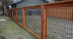 a fence that is next to a house with grass on the ground in front of it