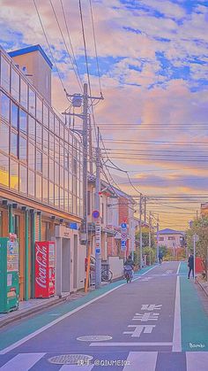 an empty street with buildings and people walking on the side walk at sunset or dawn