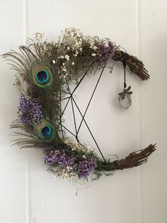 a wreath with purple flowers and peacock feathers