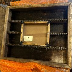 an old wooden box with rope and wood trimmings on the inside is empty