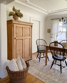 a dining room table and chairs in front of a wooden cabinet with two doors on it