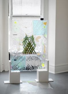 a potted plant sitting on top of white pedestals in front of a window