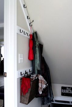 there is a coat rack with several coats hanging on it and two bags next to it