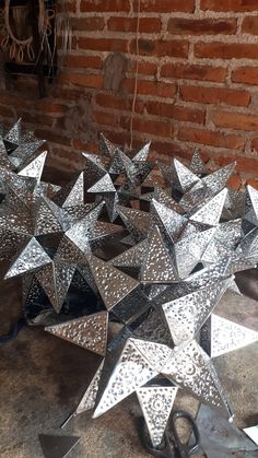 several shiny metal stars sitting on top of a wooden floor next to a brick wall