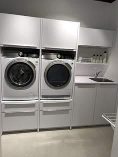 a washer and dryer in a room with white cabinets on either side of the washer