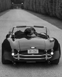 a black and white photo of a woman in a convertible car with the hood down