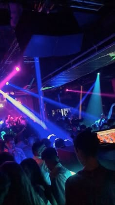 a group of people sitting in front of a crowd at a nightclub with blue and purple lights