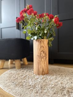 a wooden vase filled with red roses on top of a rug