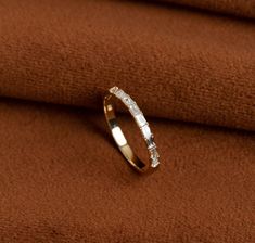 a gold ring with white diamonds on top of a brown cloth, in front of a tan background