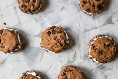 chocolate chip cookies with white frosting and chocolate chips on top are lined up on a sheet of parchment paper