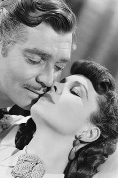 a man kissing a woman's forehead with her eyes closed in black and white