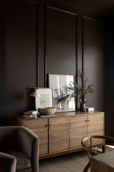 a living room with black walls and wooden furniture in the corner, along with a large mirror