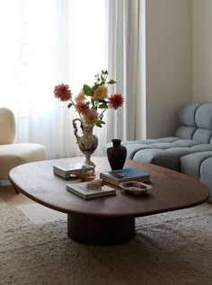 a living room with a couch, coffee table and flowers in a vase on top