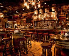 an old fashioned bar with wooden stools and lights hanging from the ceiling above it