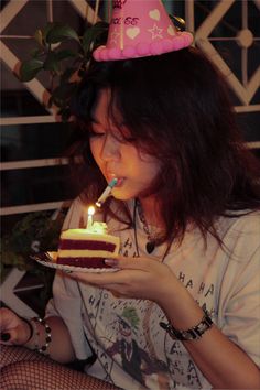 a woman blowing out the candles on her birthday cake with a candle in her mouth