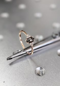 a diamond ring sitting on top of a metal table next to a screwdriver