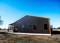 a black metal building sitting on top of a grass covered field under a blue sky