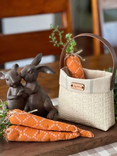 a basket with carrots sitting next to a small rabbit figurine on a table