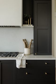 a kitchen with black cabinets and white counter tops is pictured in this image, there are wooden utensils on the cabinet doors