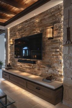 a living room with stone walls and a flat screen tv mounted to the side of it