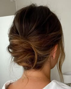 the back of a woman's head, with her hair in a low bun