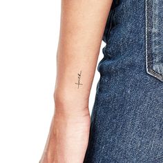 a woman's arm with a cross tattoo on the left side of her arm