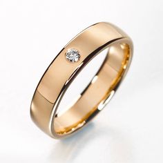 a gold wedding ring with a diamond on the inside and outside, against a white background