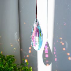 a glass hanging ornament in the shape of a tear hangs from a wire