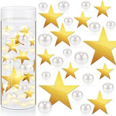 gold stars and pearls in a glass vase with white balls on the floor next to it