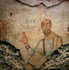 an old painting on the side of a building shows a man with a beard pointing at something