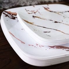 three white plates sitting on top of a wooden table covered in brown and white paint