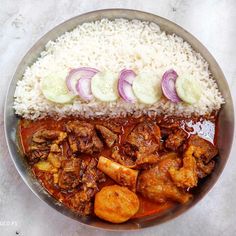 a bowl filled with rice and meat next to sliced cucumbers on top of it