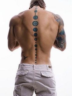 a man with his back turned to the camera and tattoos on his upper half, looking down