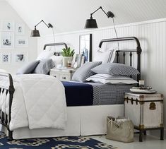 a bedroom with white walls, blue and white bedding and black iron bedspreads