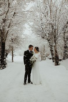 a bride and groom standing in the snow